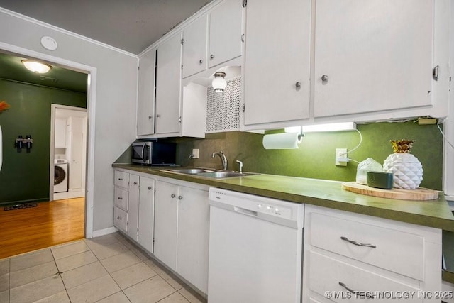 kitchen featuring light tile patterned floors, stainless steel microwave, white cabinetry, a sink, and dishwasher