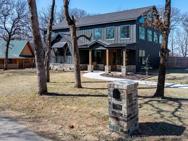 modern farmhouse style home featuring a shingled roof, a porch, board and batten siding, a front yard, and fence