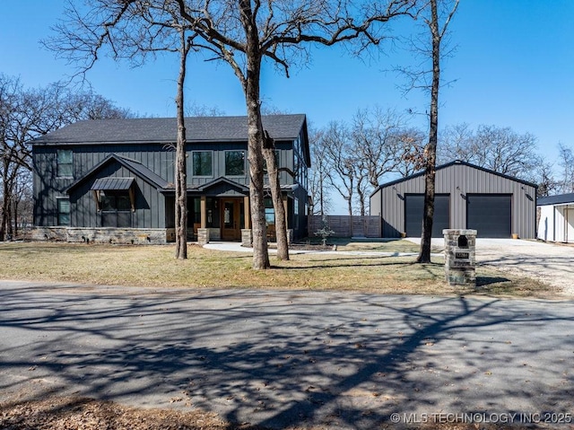 view of front of property with a detached garage, fence, board and batten siding, and an outbuilding