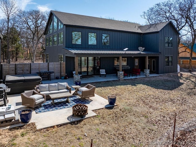 back of house featuring board and batten siding, an outdoor living space with a fire pit, a patio, and fence