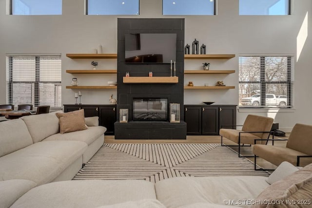 living area featuring a high ceiling and a glass covered fireplace