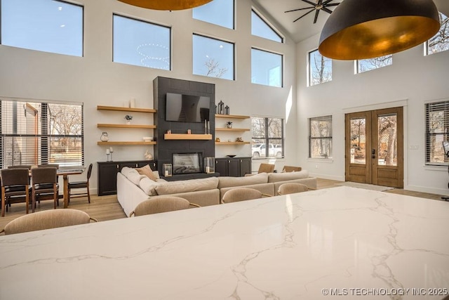 living area featuring a glass covered fireplace, french doors, plenty of natural light, and wood finished floors