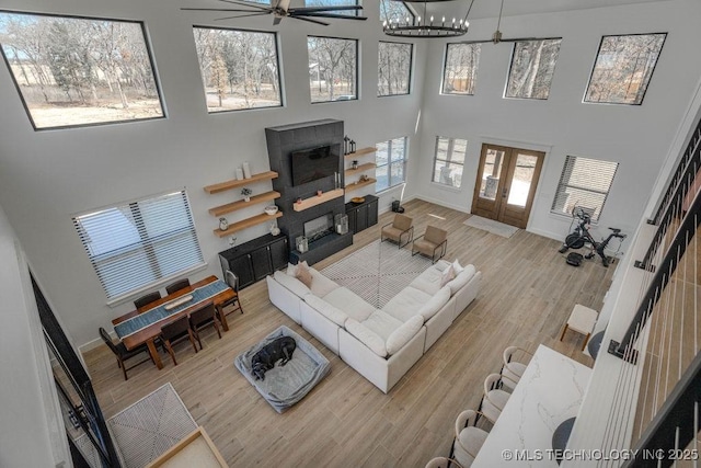 living room featuring baseboards, a towering ceiling, wood finished floors, an inviting chandelier, and french doors