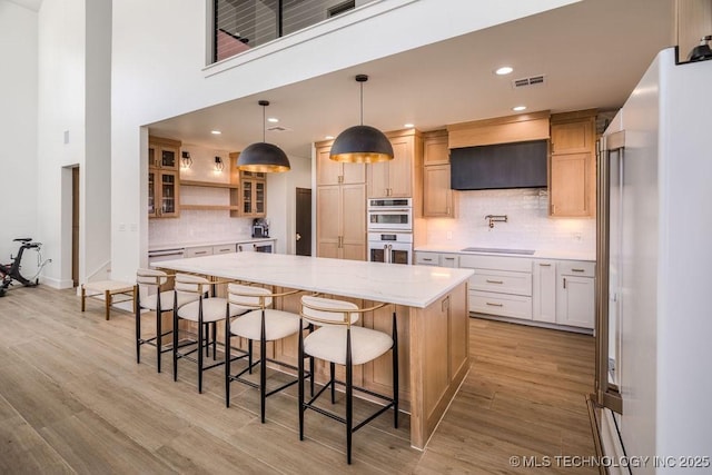 kitchen with a breakfast bar area, a spacious island, visible vents, light wood-type flooring, and white appliances