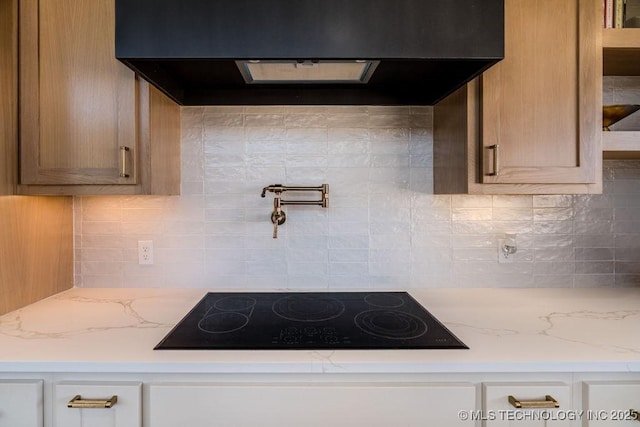 kitchen featuring light stone counters, tasteful backsplash, exhaust hood, and black electric cooktop