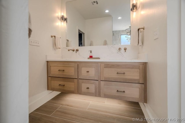 full bath featuring double vanity, baseboards, visible vents, backsplash, and a sink