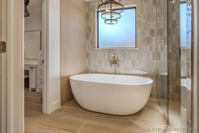 bathroom featuring a freestanding tub, tile walls, and wood finished floors