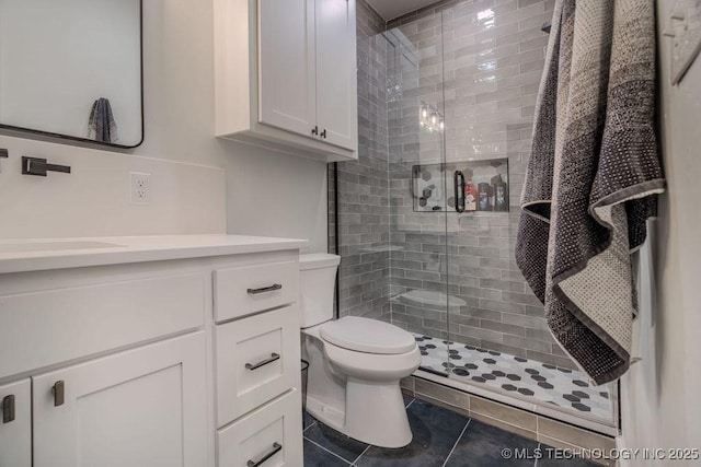 full bath featuring toilet, a shower stall, vanity, and tile patterned floors