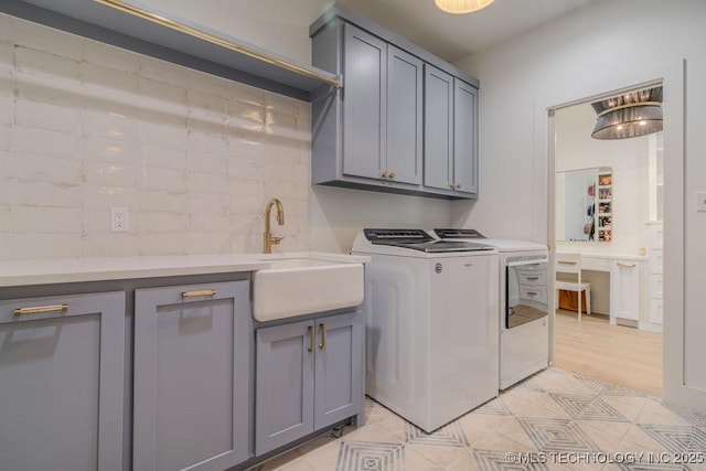 washroom with cabinet space, separate washer and dryer, and a sink