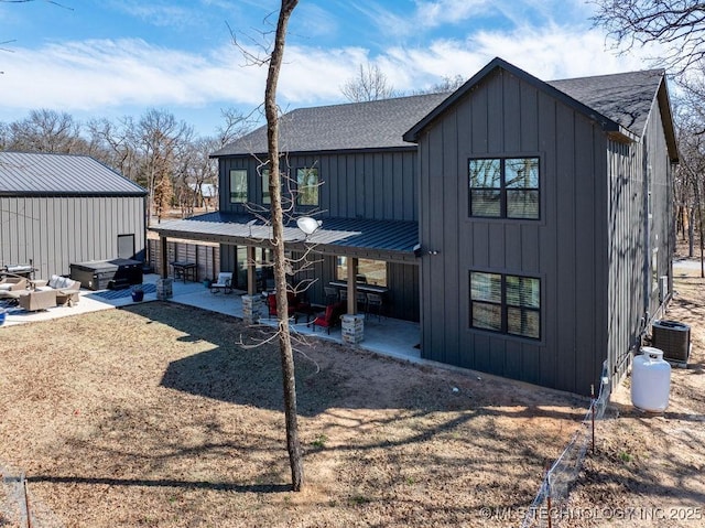 rear view of property featuring central air condition unit, a patio area, a shingled roof, and board and batten siding