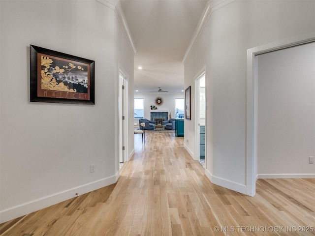 hallway featuring ornamental molding, baseboards, and wood finished floors