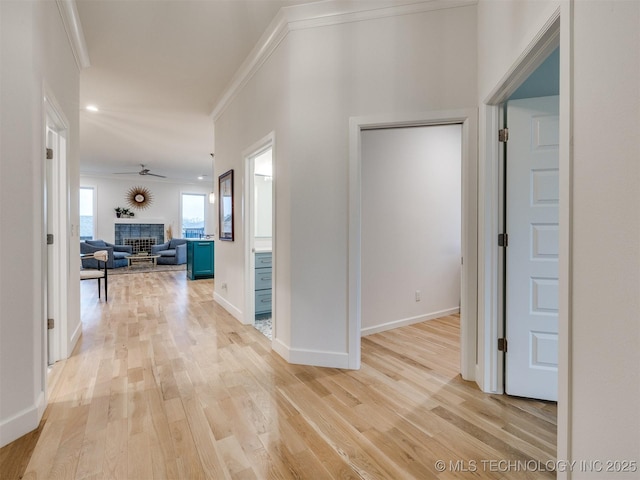 hallway featuring light wood finished floors, baseboards, ornamental molding, and recessed lighting