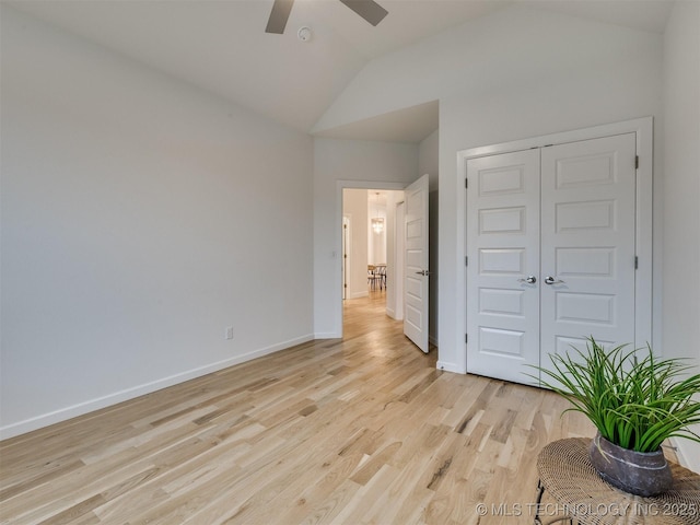 unfurnished bedroom featuring baseboards, a ceiling fan, lofted ceiling, light wood-style floors, and a closet