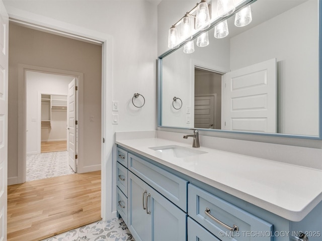 bathroom featuring a closet, wood finished floors, vanity, and baseboards