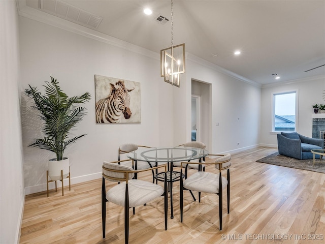 dining space with visible vents, ornamental molding, light wood-style flooring, and baseboards