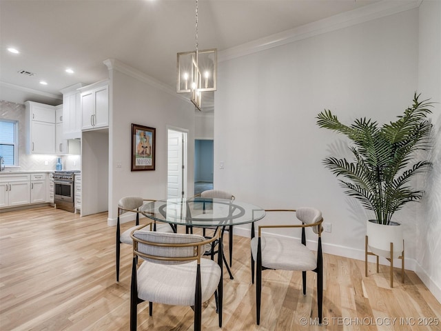 dining space with light wood-style flooring, visible vents, and ornamental molding