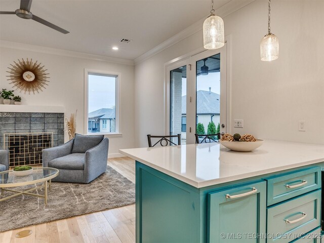 kitchen featuring ceiling fan, a tiled fireplace, visible vents, and crown molding