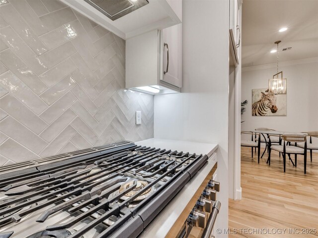 kitchen featuring light wood-style floors, light countertops, decorative backsplash, decorative light fixtures, and an inviting chandelier