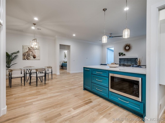 kitchen with light wood-style floors, light countertops, ornamental molding, blue cabinetry, and built in microwave