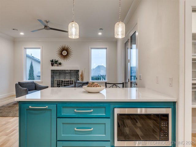 kitchen with visible vents, a tile fireplace, stainless steel microwave, open floor plan, and ornamental molding