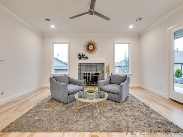 living area with a wealth of natural light, visible vents, and crown molding