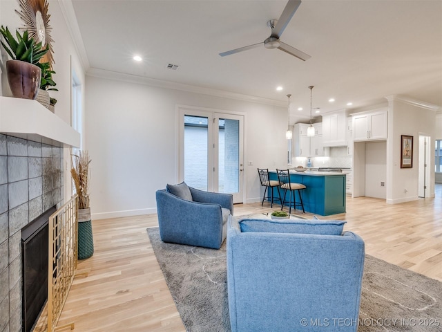 living area with crown molding, visible vents, and a tiled fireplace