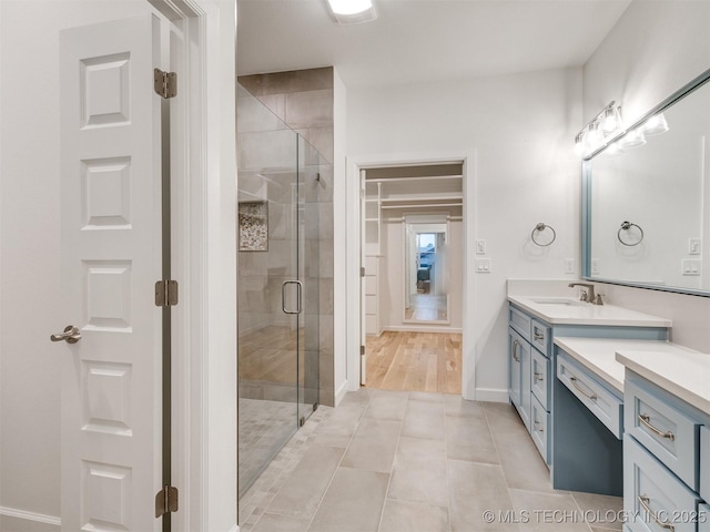 bathroom featuring tile patterned flooring, a shower stall, vanity, and baseboards