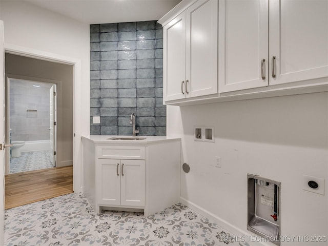 clothes washing area featuring cabinet space, a sink, hookup for a washing machine, hookup for an electric dryer, and tile walls