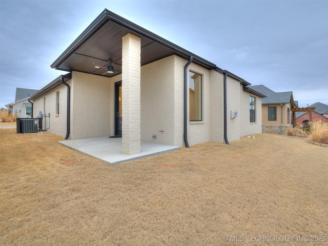 back of property with a patio area, ceiling fan, central AC unit, and brick siding