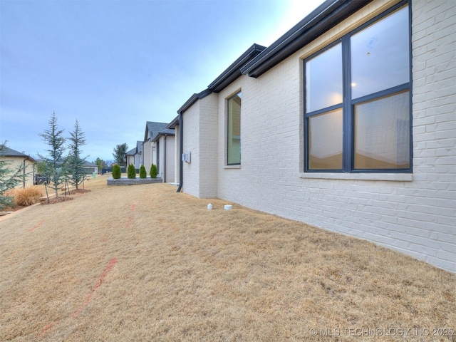 view of side of home with brick siding and a yard