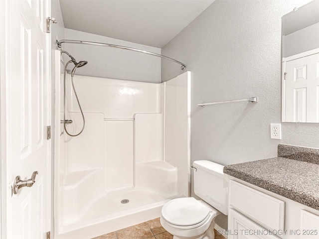 full bath featuring a shower, a textured wall, toilet, tile patterned floors, and vanity