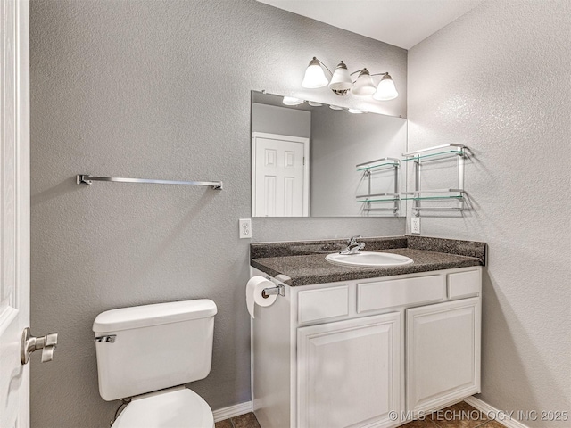 half bathroom with a textured wall, vanity, toilet, and baseboards