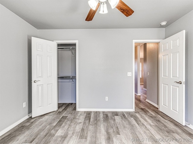 unfurnished bedroom featuring ceiling fan, a closet, wood finished floors, and baseboards