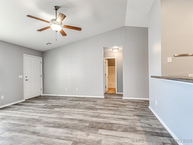 spare room featuring lofted ceiling, ceiling fan, wood finished floors, visible vents, and baseboards