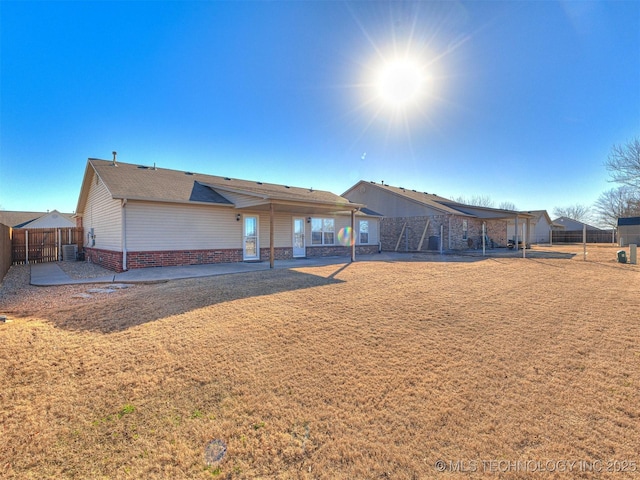 rear view of property featuring a yard, a patio area, and fence