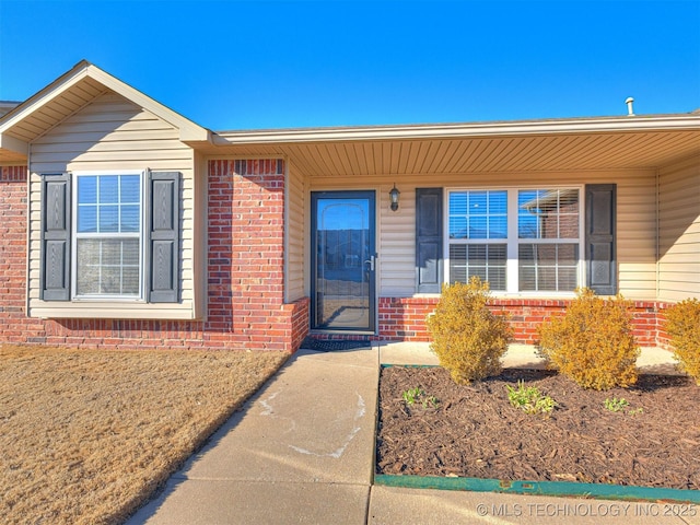 entrance to property featuring brick siding and a yard