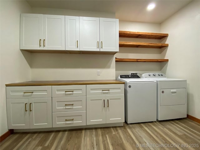 clothes washing area with light wood-style floors, cabinet space, washer and clothes dryer, and baseboards