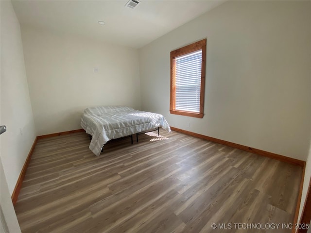 bedroom with visible vents, baseboards, and wood finished floors