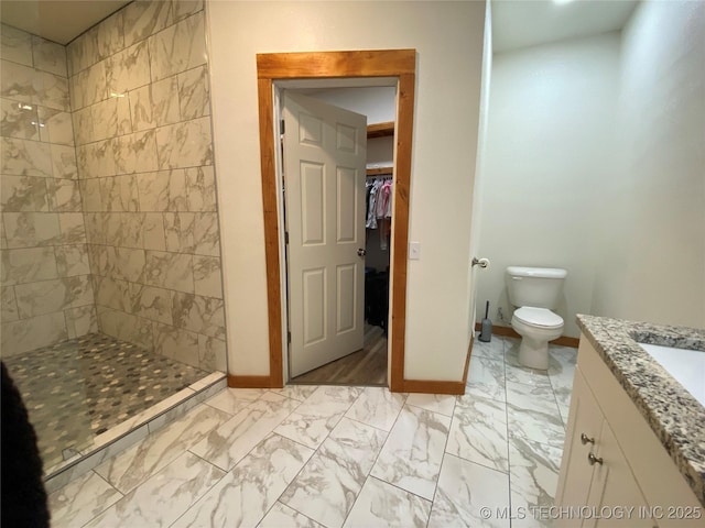 bathroom with toilet, baseboards, marble finish floor, a spacious closet, and a stall shower