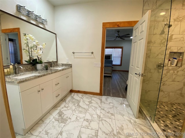 bathroom featuring marble finish floor, a tile shower, and a sink