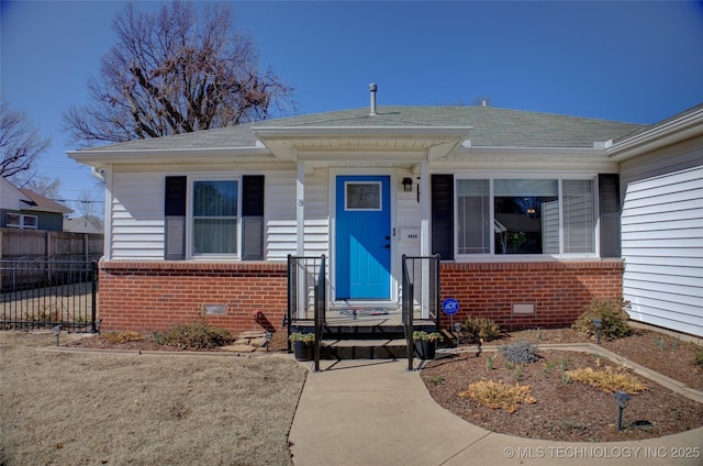 doorway to property featuring roof with shingles, brick siding, crawl space, and fence