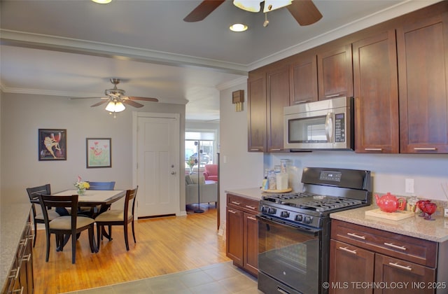 kitchen featuring crown molding, stainless steel microwave, a ceiling fan, gas stove, and light stone countertops