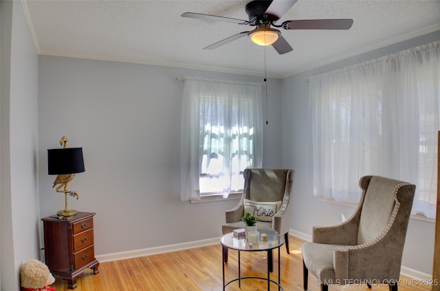 living area with a textured ceiling, light wood finished floors, and baseboards