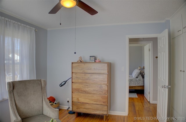 sitting room featuring crown molding, a textured ceiling, baseboards, and wood finished floors