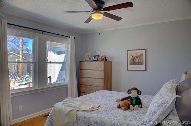 bedroom with a textured ceiling, wood finished floors, visible vents, baseboards, and crown molding