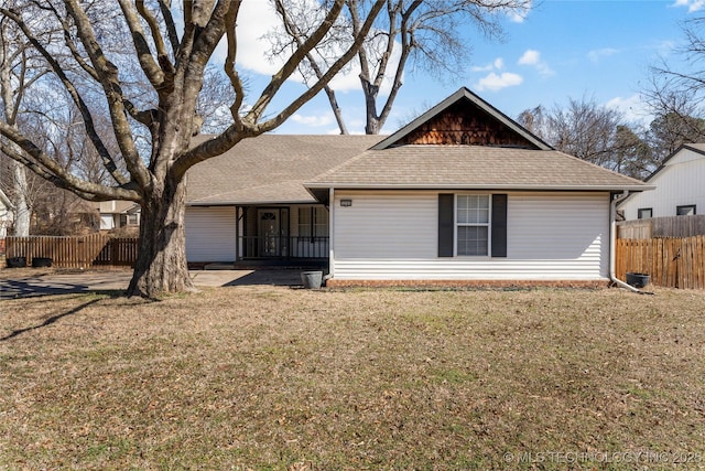 ranch-style home featuring a shingled roof, a front yard, and fence