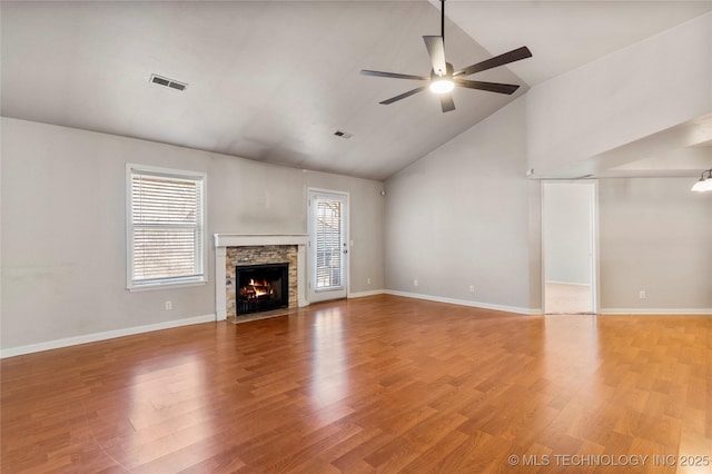 unfurnished living room featuring ceiling fan, light wood-style flooring, a fireplace, and a wealth of natural light