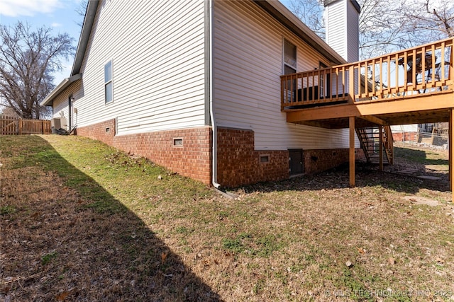 view of side of property with fence, a yard, crawl space, a wooden deck, and a chimney