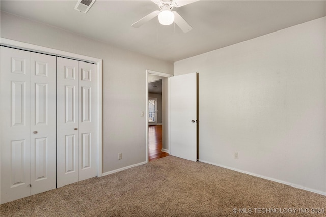 unfurnished bedroom featuring a closet, carpet flooring, visible vents, and a ceiling fan