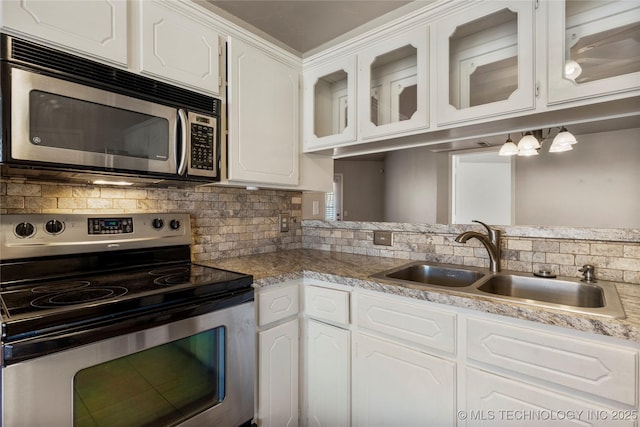 kitchen with stainless steel appliances, a sink, white cabinets, backsplash, and glass insert cabinets